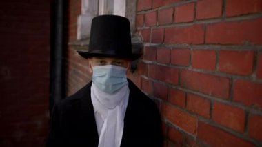 Güzel bir genç adam, frak giyiyor ve şapkasını çıkartıyor.