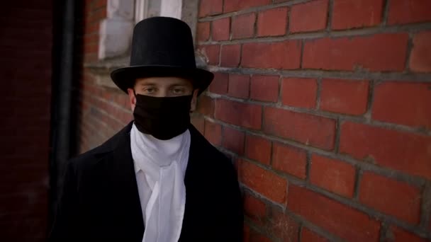 Красивый молодой человек в пальто и шляпе, снимающий маску с лица — стоковое видео