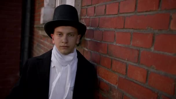 コートを着たハンサムな若い男と彼の顔のマスクを置くトップ帽子 — ストック動画