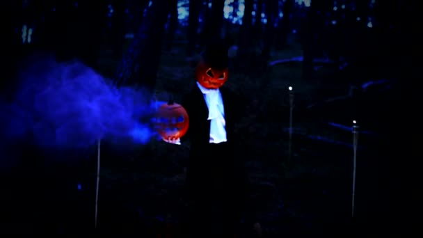 Upiorny dynia głowica człowiek trzymając a ogromny dynia z niebieski dym w las — Wideo stockowe