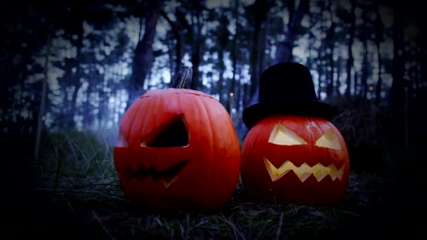 Dos espeluznantes calabazas talladas para Halloween ardiendo con humo en el bosque — Vídeo de stock