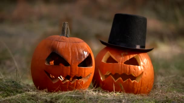 Dos espeluznantes calabazas de Halloween que yacen en la hierba Una de ellas está ardiendo en su interior — Vídeo de stock