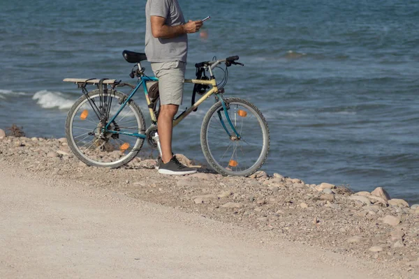 Perona bisikletiyle cep telefonuna bakıyor.