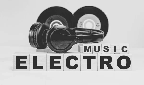 ELECTRO music inscription on wooden cubes on the background of vinyl records and headphones. Musical concept.