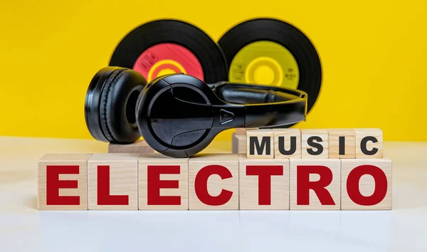 ELECTRO MUSIC inscription on wooden cubes on the background of vinyl records and headphones. Musical concept.