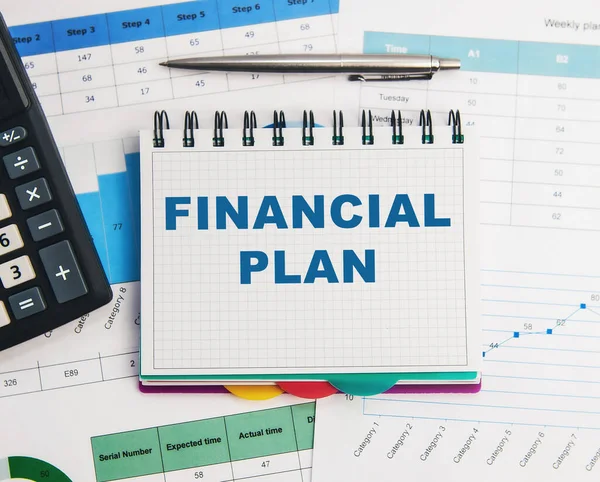 The text of the financial plan in a notebook on the background of a calculator, pen and financial papers.
