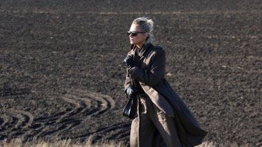 ıssız bir alanda bir tepe üzerinde takım elbiseli kadın