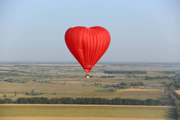 红色热气球形状的心脏在乌克兰的田野上飞来飞去 — 图库照片