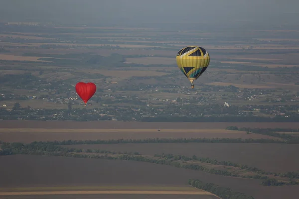 Red hot air balloon in the shape of a heart flies over the fields of Ukraine