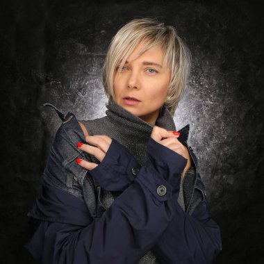 Lüks bir şekilde giyinmiş portre sarışın saç kesimi üzerinde karanlık bir arka plan, güzel Studio ile modern kadın 40 +, bakımlı ve çekici