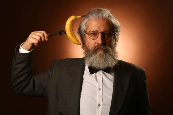 Retrato de un anciano caballero de pelo gris, con bigote y barba peluda, con camisa blanca y chaqueta gris, con gafas y tenedor Fotos de stock