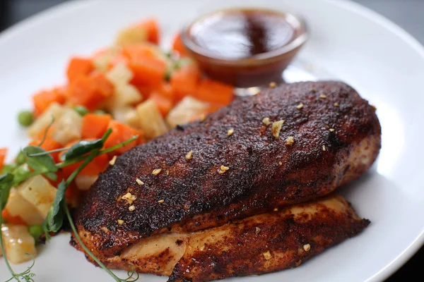 Filete de pollo, al horno con especias y cubierto con una corteza apetitosa, en un plato con verduras y salsa Imagen de stock