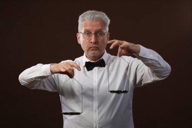 50 yaşlarında, beyaz gömlek, gözlük ve papyon bir şey kettlebells pullarla üzerinde ağırlığında gri saçlı yaşlı adam