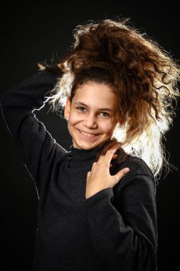 Duygusal bir siyah arka plan üzerine uzun kıvırcık saçlı bir kız portresi,