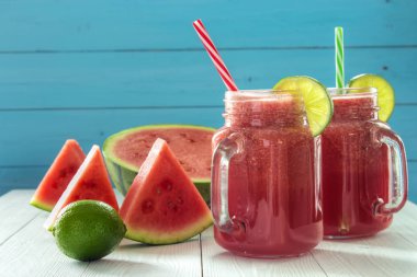 Karpuz smoothies ile meyve dilimleri ve kireç kireç dilimleri ile dekore edilmiş beyaz tahta masada
