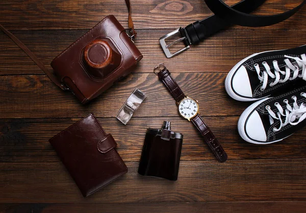 fashion. watches, wallets, belt, cologne, sneakers and old camera on a wooden background