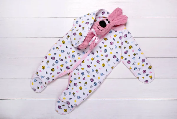 baby pajamas and a knitted toy on a white background
