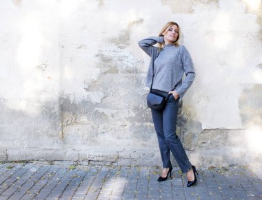 moda. trendy bir kazak ve pantolon duvarın yanında genç kadın