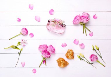 Moda. Beyaz ahşap arka planda mis kokulu parfüm ve güller