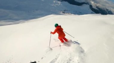 Dişi alp kayakçısı pudra yamacından iniyor ve dönüşler yapıyor. Kadın kayakçı İspanyol Pireneleri 'nde eğleniyor. Birinci şahıs görünümü, geniş açı ile orta açı.