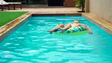 8 yaşında bir çocuk büyük bir şamandırada havuzda dinleniyor. Güneşli bir yaz günü..