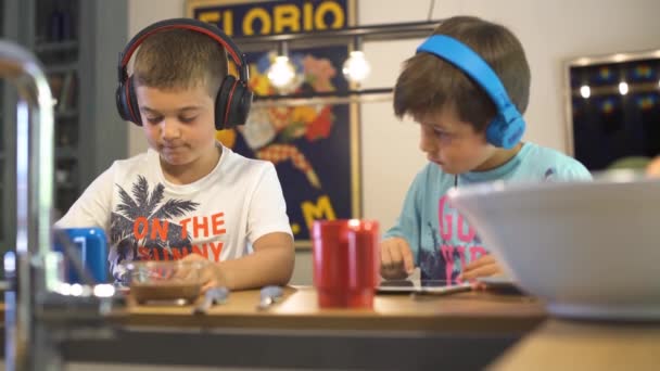 Két Fejhallgatós Gyerek Játszik Tabletjeikkel Beszélnek Videojátékokról Konyhában Vannak Épp — Stock videók