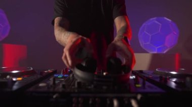 Erkek DJ, koyu mor bir atmosferde kulaklık takıyor. Disk jokeyi hazırlanıyor.