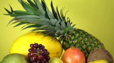 Renkli sarı bir arka planda taze tropikal meyve seti. Üzüm, kavun, elma, ananas, muz, hindistan cevizi, mango, limon ve greyfurt..
