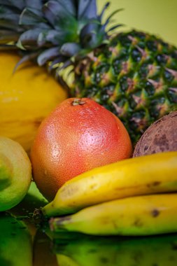 Renkli sarı bir arka planda greyfurt ve taze meyve seti. Farklı meyvelerden oluşan dikey çekim.