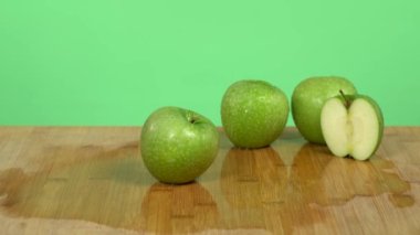 Beyaz eller bir bıçak gösteriyor ve yeşil bir elmanın yarısını hızlı ve temiz bir şekilde kesiyor. Yeşil stüdyo geçmişi.