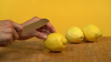 Sarı stüdyo arka planında yarım limonla kesilmiş bıçaklı beyaz eller..