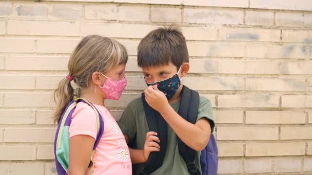 5岁的孩子戴着防护口罩在学校外说话 男孩调整了口罩以正确地放置口罩 科罗纳韦勒斯大流行病期间返回学校 — 图库视频影像