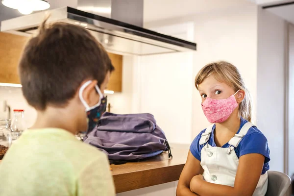 6-years-old caucasian girl with colored protective mask looking at camera. Preschool Kids in house kitchen. Daytime, first day of school after coronavirus pandemic. New rules Covid-19.