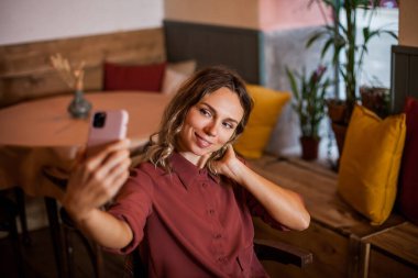 Çekici sarışın genç bir kadının bir kafede selfie çekerken yakın plan portresi..