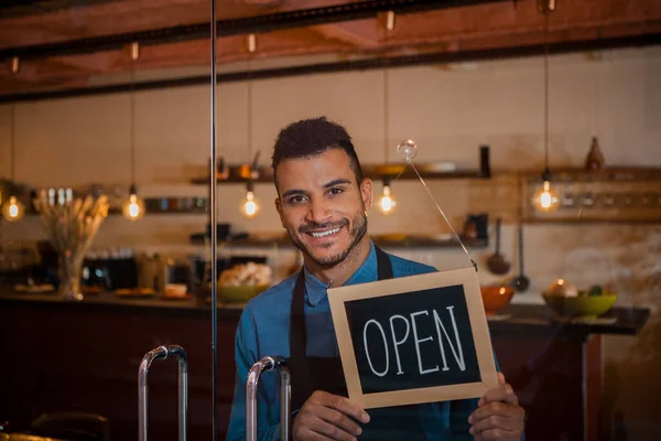 Portrait Smiling Business Man Looking Camera Putting Open Sign Glass — Stock Photo, Image