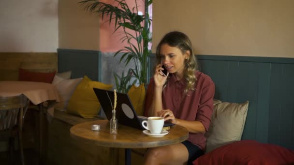 微笑的女商人在电话里聊天 在咖啡店用她的笔记本电脑工作 忙碌的年轻女性自由职业者在办公室工作 通信和技术概念 — 图库视频影像
