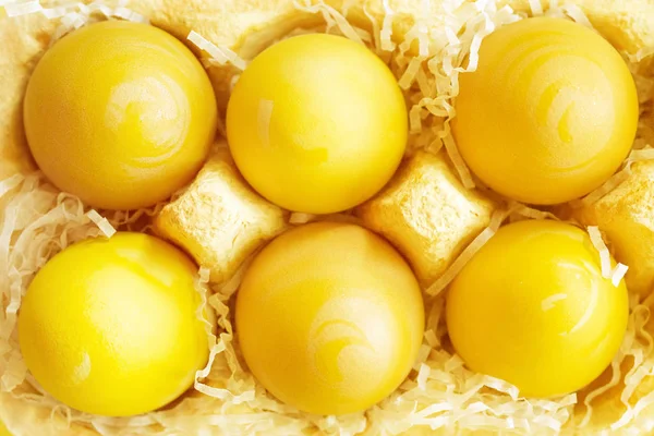 Easter yellow eggs in an egg container on a yellow background, top view