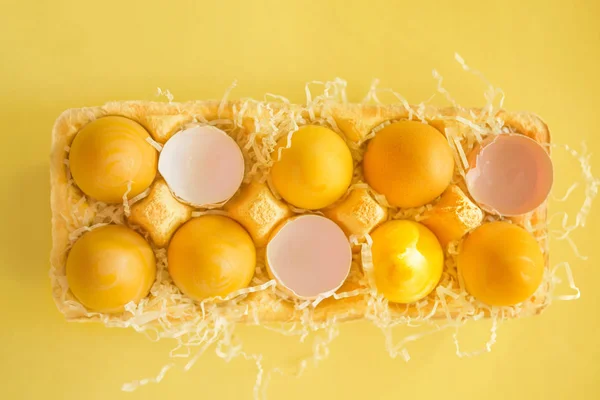 Easter yellow eggs in an egg container on a yellow background, top view