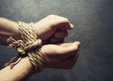 Erkek eller tarafından koyu arka plan yakın çekim kaba bir ipe bağlı. Esaret, kölelik sembolü