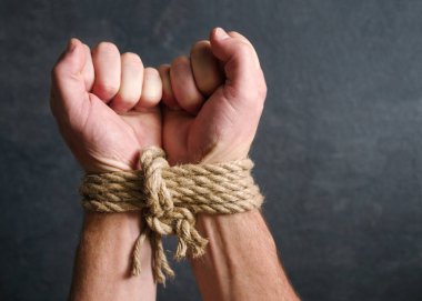 Erkek eller tarafından koyu arka plan yakın çekim kaba bir ipe bağlı. Esaret, kölelik sembolü