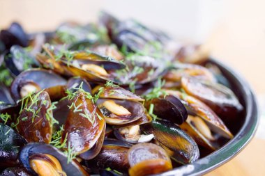 Bir plaka üzerinde yeşillikler ile pişmiş midye, deniz ürünleri, yumuşak odak