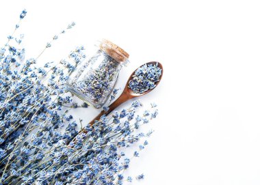 Cam şişe ve beyaz ahşap arka plan üzerinde lavanta ile kurutulmuş lavanta çiçekleri ve buket ile ahşap kaşık