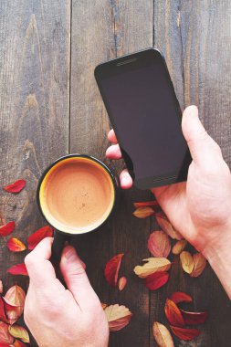 Telefon ve bir masa üzerinde kahve bir fincan ile Erkek eller, üst görünümü