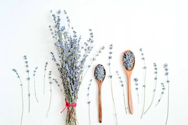 Wooden spoons with dried lavender blossoms and bouquet with lavender on white background top view