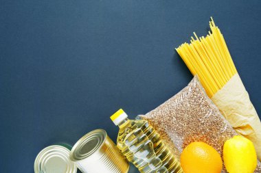 Yiyecek bağışları - yağ, karabuğday, makarna, meyve, mavi arka planda konserve yiyecekler, fotokopi alanı olan üst manzara. Yiyecek teslimatı kavramı.