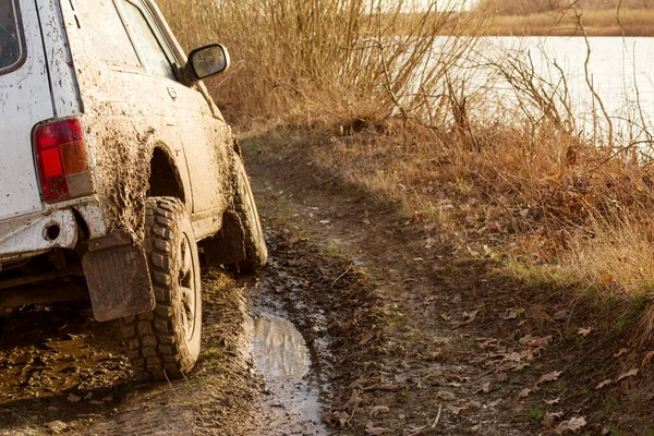 Dirty SUV is driving off-road with puddles and dirt close-up. Off-road travel