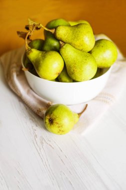  Tahta masadaki beyaz kasede taze armutlar.