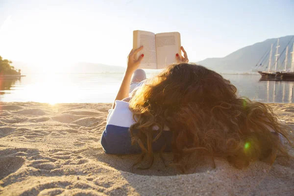 Νεαρή γυναίκα διαβάζει βιβλίο στην παραλία — Φωτογραφία Αρχείου