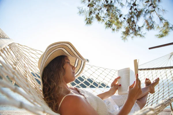 Mujer en una hamaca con libro de vacaciones —  Fotos de Stock