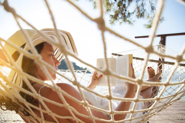 Mujer en una hamaca con libro de vacaciones —  Fotos de Stock